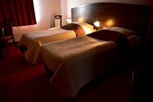 2 camas en una habitación de hotel con luces encendidas en Hotel Nekla en Nekla