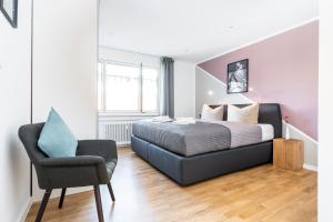 1 dormitorio con 1 cama y 1 silla en Deluxe Apartments Friedrichstrasse, en Freiburg im Breisgau