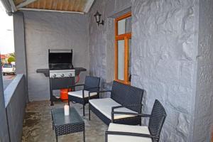 a patio with chairs and a table and a stove at FlowerBox Cottages in Mossel Bay