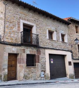 Edificio de piedra con 2 puertas y balcón en Casa Rural El Tinte, en Sigüenza