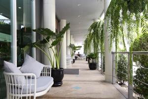 ラートクラバンにあるミラクル スワンナブーム エアポートの白い椅子と植物のある廊下