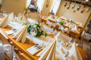 uma sala de jantar com uma mesa com toalhas de mesa brancas e copos em Penzion Restaurace u Helferů em Libuň