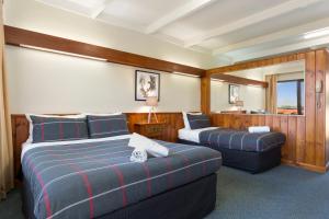 a hotel room with two beds and two couches at Village Family Motor Inn in Launceston
