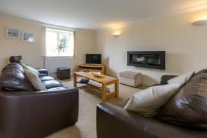 a living room with two leather couches and a fireplace at Meadow View, Near Aldeburgh in Aldringham