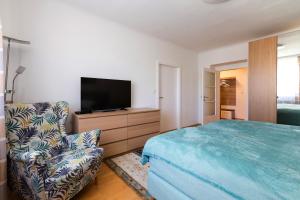 1 dormitorio con 1 cama, 1 silla y TV en Apartment Rudolfsplatz, en Viena