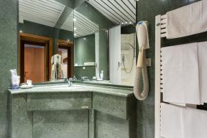 un bagno con un lavandino e un grande specchio di Albergo Il Cacciatore a Spello