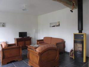 a living room with a fireplace and two chairs at Le Bosvillais in Bosville