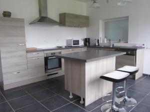 a kitchen with a counter and two bar stools at Le Bosvillais in Bosville