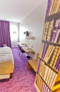 um quarto de hotel com uma cama e uma estante de livros com livros em Hôtel Anne De Bretagne em Rennes