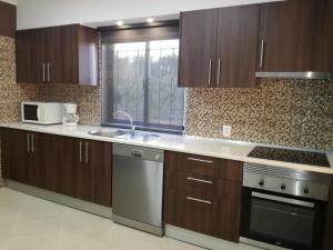 a kitchen with wooden cabinets and a sink and a microwave at Quinta Vita - Vila Uva in Almancil