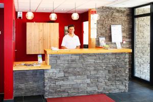 a man standing behind a bar in a restaurant at Résidence Néméa L'Aigle Bleu in Briançon