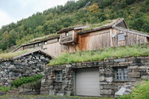 a stone building with a grass roof with a garage at Ein heilt spesiell låve i Røldal in Røldal
