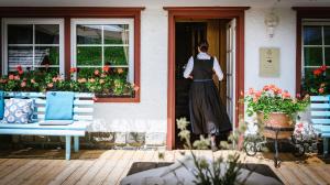 a woman walking out of a house door at Berghotel Ladinia in Corvara in Badia