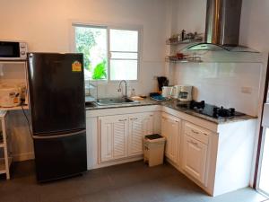 a kitchen with a black refrigerator and a sink at Hibiscus Cottage in Ban Dan Kao