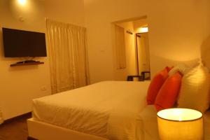 a bedroom with a white bed with a flat screen tv at The Tamarillo in Ooty