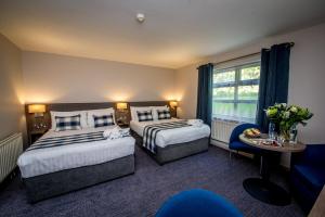 a hotel room with two beds and a table at Waterfoot Hotel in Derry Londonderry