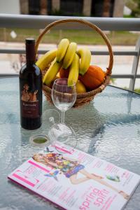 ハニオティスにあるApartments Eleni 4 Seasonsのフルーツバスケット、ワイン1本(テーブル上)