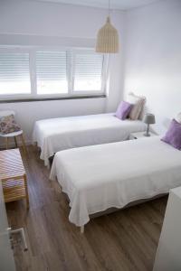 ポルティマンにあるFantástico apartamento a 200m da Praiaの白い壁と窓が備わる客室で、ベッド2台が備わります。