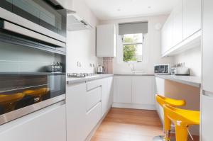a kitchen with white cabinets and yellow chairs at Dalkeith Three Bed Two Bath Apartment in Dalkeith