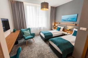 um quarto de hotel com duas camas e uma cadeira em K4 APARTHOTEL KRAKÓW na Cracóvia