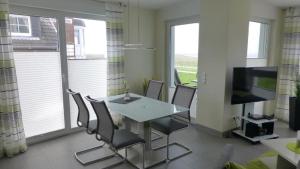 ein Esszimmer mit einem Tisch, Stühlen und einem TV in der Unterkunft Residenz Windjammer Whg 12 in Cuxhaven