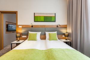 um quarto com uma cama grande e almofadas verdes em K4 APARTHOTEL KRAKÓW em Cracóvia