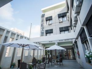 two tables and chairs with umbrellas in front of a building at Rainbow Hotel in Magong