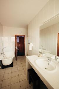 a bathroom with two sinks and a tub and a bath tub at Hotel Schweizerhaus/Cafe Anton in Swakopmund