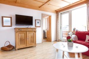 a living room with a red couch and a tv at Ferienwohnungen Alpentraum - Hörnernest in Bolsterlang