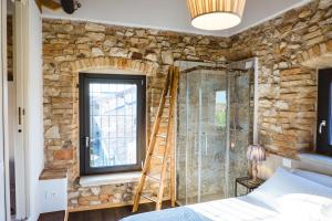 una camera da letto con parete in pietra e scala accanto a una finestra di Villa Colli Storici a Desenzano del Garda