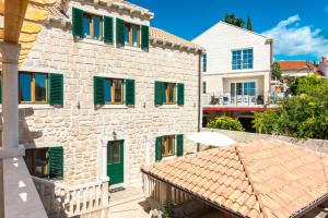 ein Gebäude mit grünen Fensterläden und einem Dach in der Unterkunft Apartments Villa Kulish in Cavtat