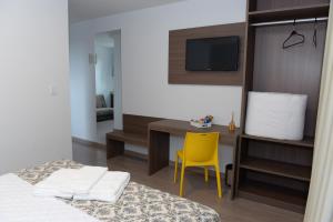 a bedroom with a bed and a desk and a yellow chair at Hotel Solar do Parque in Tabapira