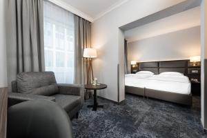 a hotel room with a bed and a chair at Wyndham Köln in Cologne