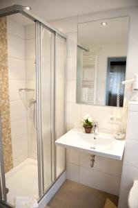 a white bathroom with a shower and a sink at Gasthof Pfauen in Oberkirch