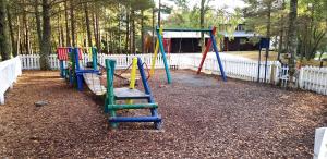 a playground with colorful swings and a white fence at Macdonald Lochanhully Resort in Carrbridge
