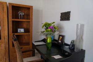 a desk with a vase of flowers on it at Birdcage Gay Men Resort and Lifestyle Hotel in Playa del Ingles