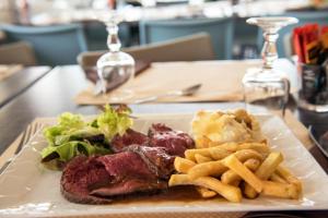 une assiette de nourriture avec un steak et des frites sur une table dans l'établissement Le Beauregard, à Brive-la-Gaillarde