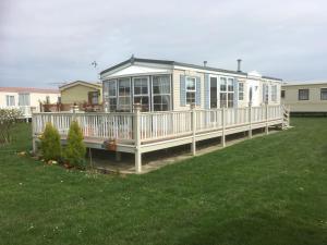 a large house with a large deck on a lawn at Golden palm resort skegness in Chapel Saint Leonards