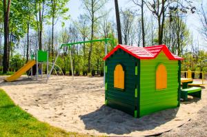 un parque infantil con una casa pequeña y un tobogán en Hotel Ossowski, en Swarzędz