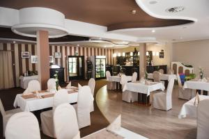 a restaurant with white tables and white chairs at Hotel Ossowski in Swarzędz