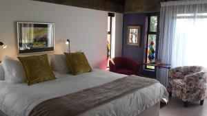 1 dormitorio con 1 cama grande y 1 silla roja en Absolute Castillo, en Riebeek-Kasteel