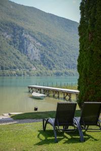 two benches sitting on the grass near a lake at Novalaise Plage in Novalaise