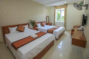 um quarto de hotel com duas camas e uma televisão em Cat Ba Green Hotel em Ilha de Cát Bà