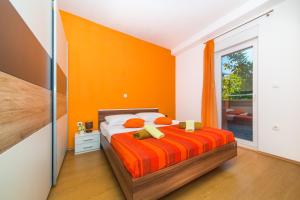 a bedroom with a bed with an orange wall at Apartment Marino in Kaštela