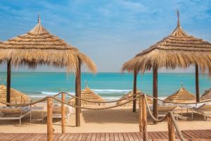 a group of straw umbrellas and chairs on a beach at Four Seasons Hotel Tunis in Gammarth