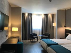 a hotel room with a bed and a desk and chairs at HG City Suites Barcelona in Barcelona