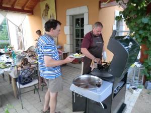 two men are preparing food on a grill at La Bastide de Fontaille in Saint-Félicien