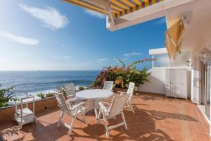un patio con mesa y sillas con vistas al océano en Exclusive frontline one bedroom apartment, en Puerto de Santiago