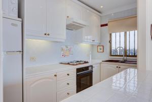 cocina blanca con armarios blancos y nevera en Exclusive frontline one bedroom apartment, en Puerto de Santiago