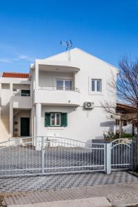 a white house with a fence in front of it at Apartments Franičević in Sućuraj